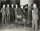 Photo of men watching television demonstration.
